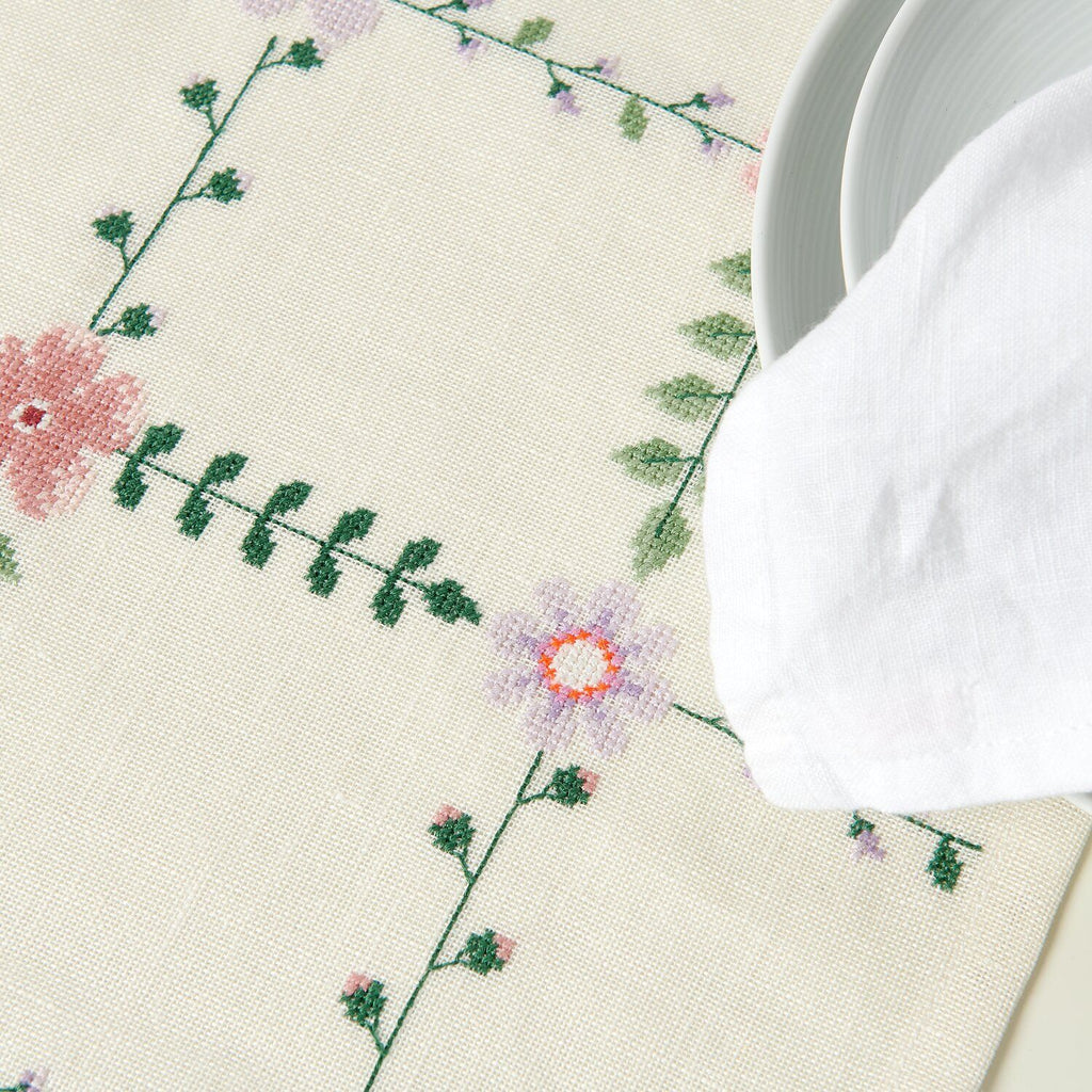 Camino de mesa blanco de 42x164cm bordado a punto de cruz con delicadas flores silvestres en tonos rosa y verde, parte del kit de Rico Design.