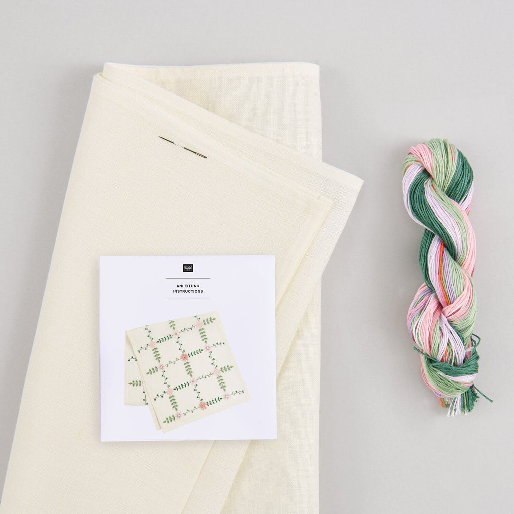 Camino de mesa blanco de 42x164cm bordado a punto de cruz con delicadas flores silvestres en tonos rosa y verde, parte del kit de Rico Design.