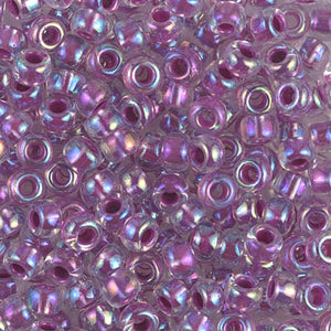 Mostacillas de vidrio japonesas Miyuki calibradas 6/0 transparentes con centro morado. Acabado tornasol brillante, ideales para tejido con mostacillas, bordado, aplicaciones costura y bisutería artesanal. Cabeza de Alfiler, Chile.