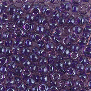 Mostacillas de vidrio japonesas Miyuki calibradas 6/0 transparentes con centro de color violeta morado opaco. Acabado brillante, ideales para tejido con mostacillas, bordado, aplicaciones costura y bisutería artesanal. Cabeza de Alfiler, Chile.