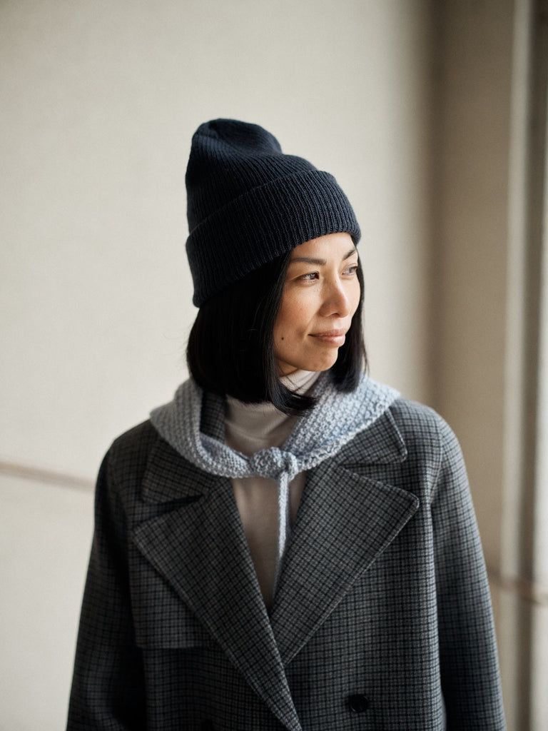 Foundations de Sari Nordlund — gorro negro y cuello gris tejidos, sobre abrigo de tweed