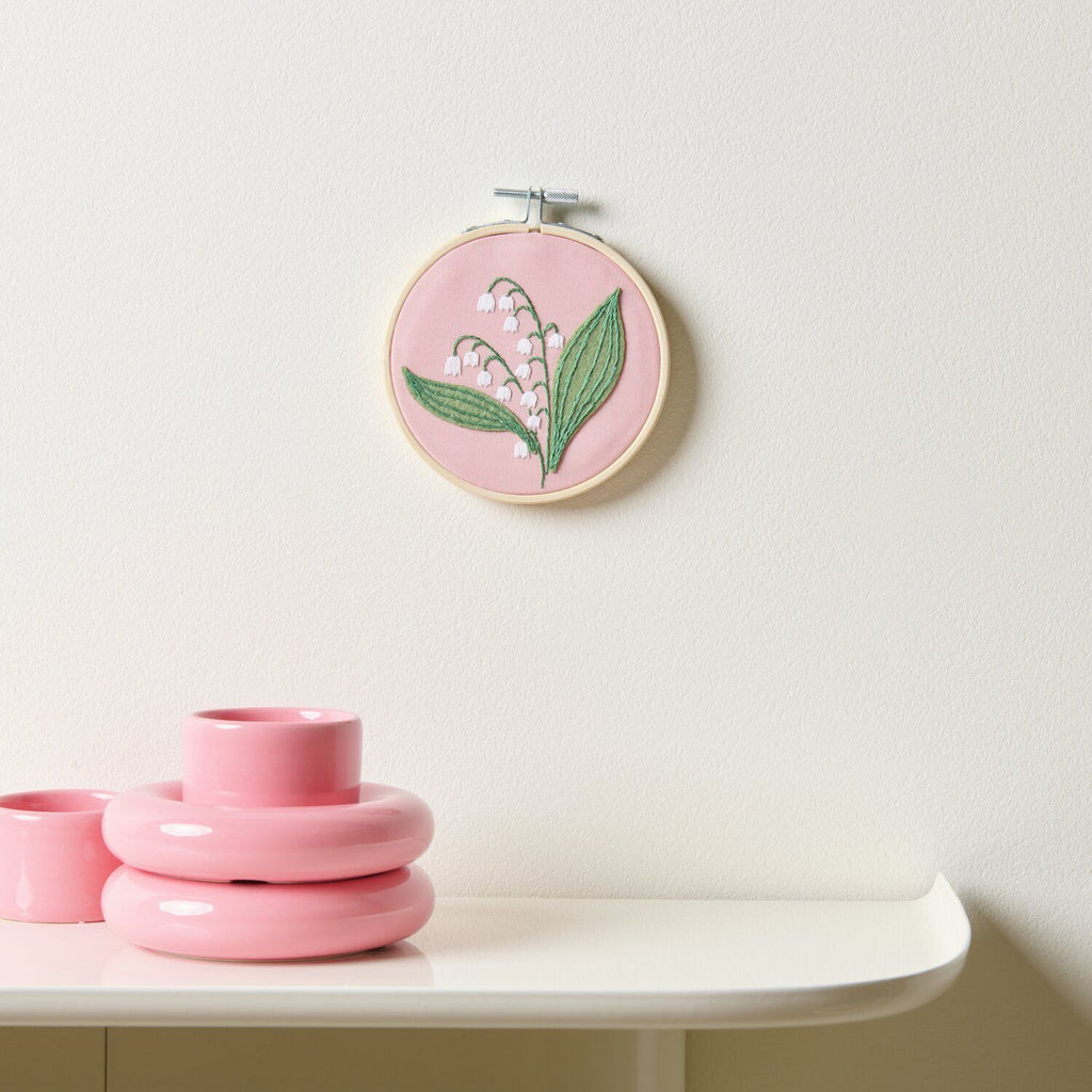Mini kit de bordado de Rico Design mostrando un delicado diseño de flores Lirios del Valle enmarcado en un bastidor de madera de 10 cm.
