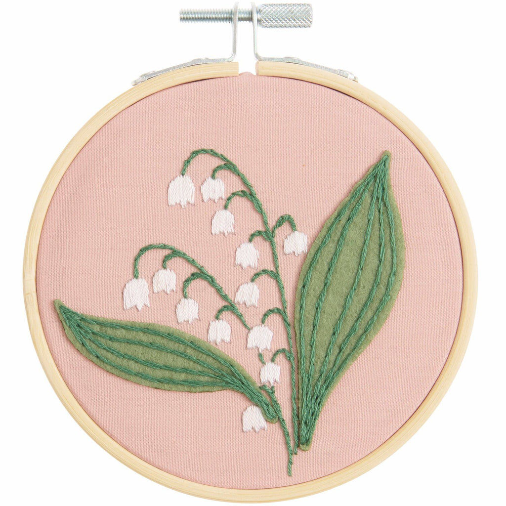 Mini kit de bordado de Rico Design mostrando un delicado diseño de flores Lirios del Valle enmarcado en un bastidor de madera de 10 cm.