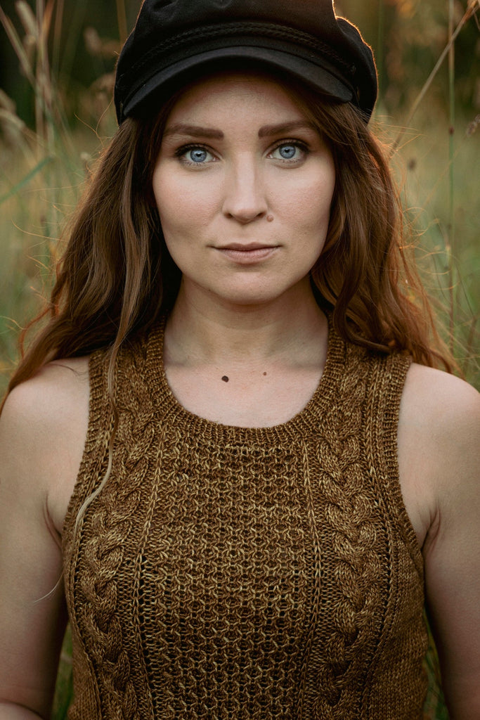 Unfolding Landscapes — top mostaza con trenzas, con gorra de visera